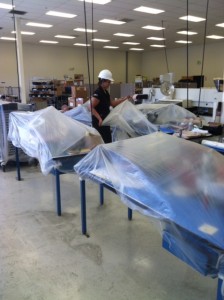 Tables covered in plastic in an office with woman in a white hardhat