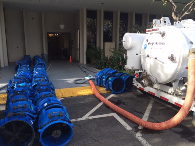 White machinery and blue fans outside a commercial building
